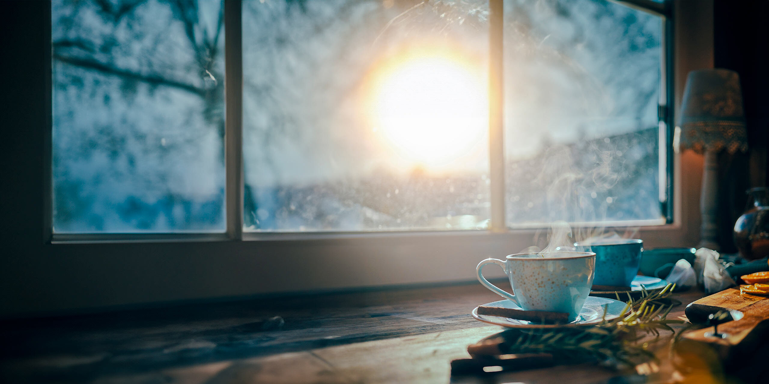 Eine dampfende Tasse Kaffee steht auf einem Tisch neben einem Fenster. Die Sonne scheint hell durch das Glas und wirft einen warmen Schein auf die Szene. Die Außenansicht ist verschwommen und suggeriert eine heitere Morgenatmosphäre.